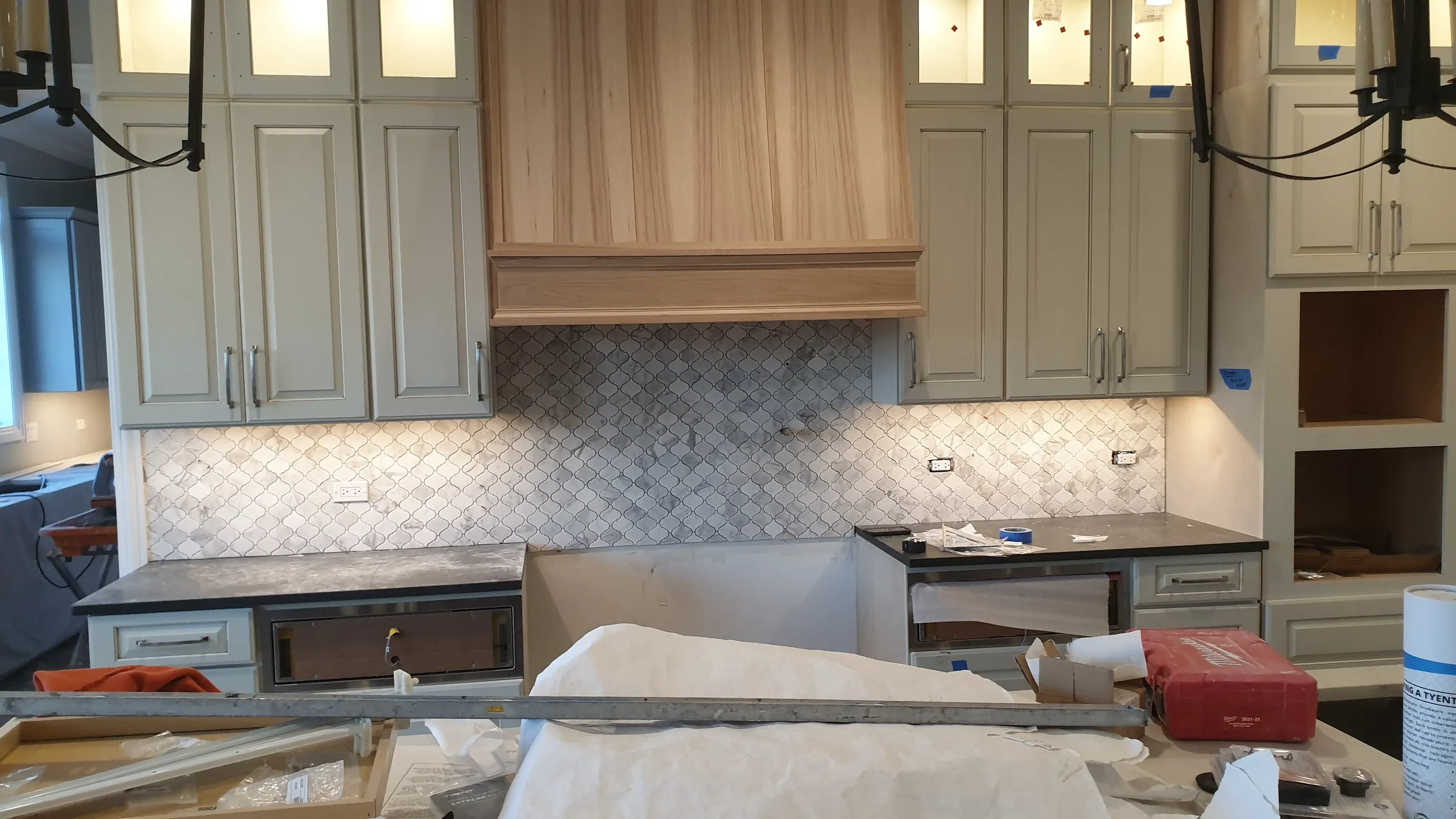 Kitchen renovation in progress with cabinets and backsplash installation visible