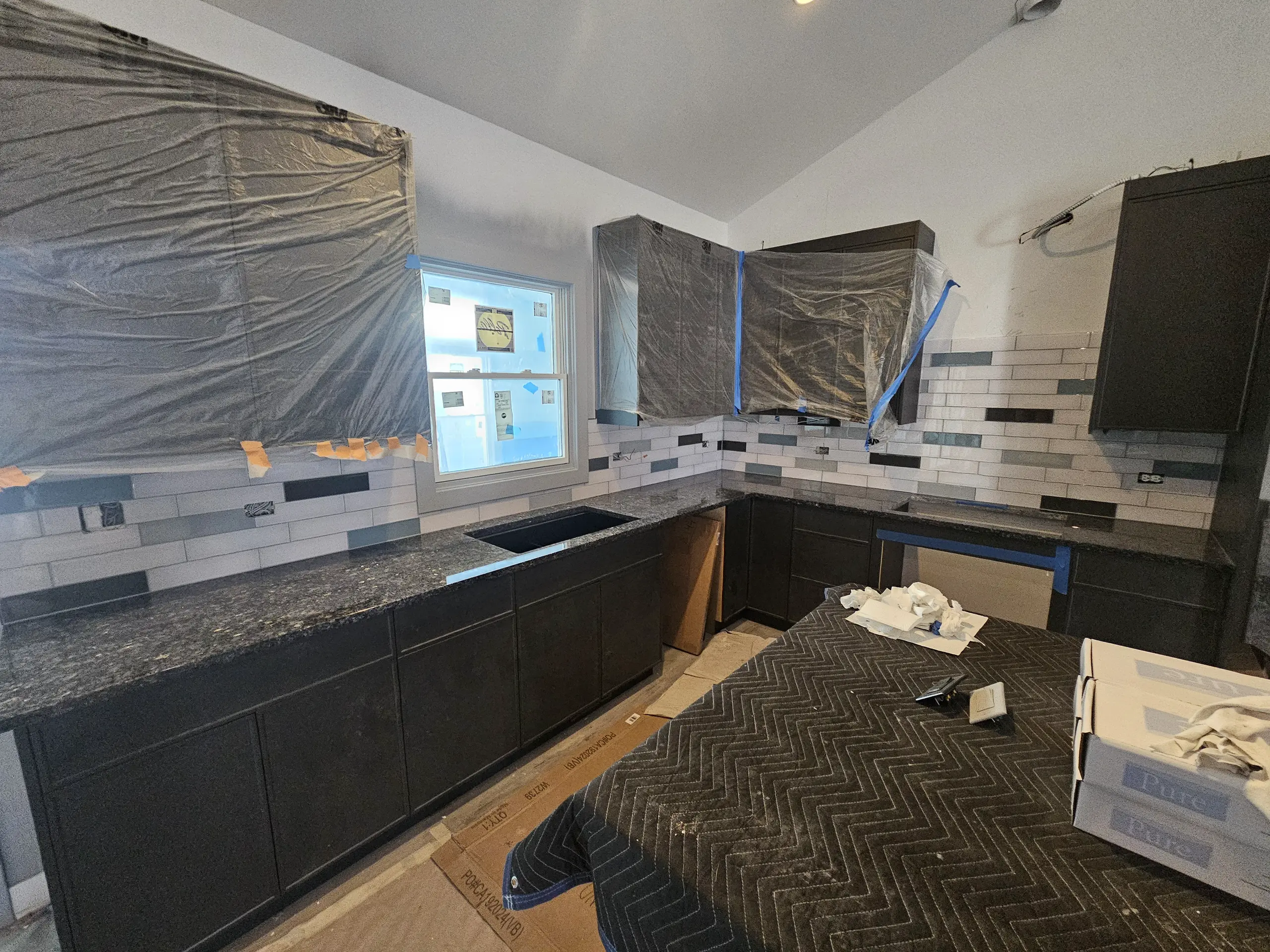 Kitchen renovation with countertops, cabinets, and backsplash installation in progress
