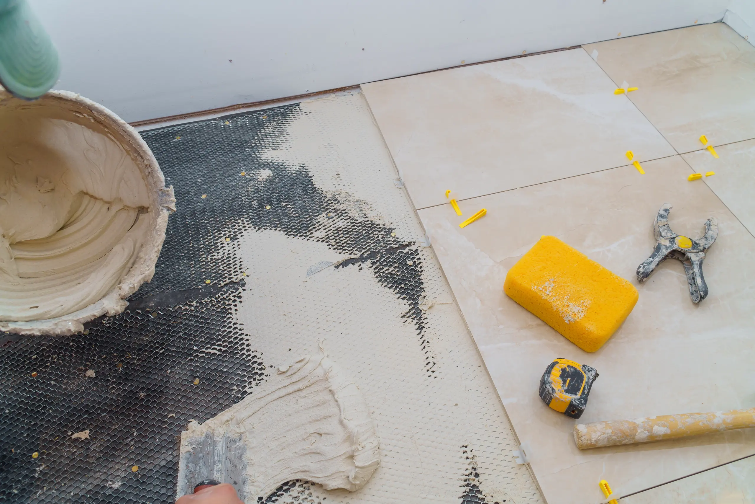 Worker applying tile adhesive on a floor during tile installation process