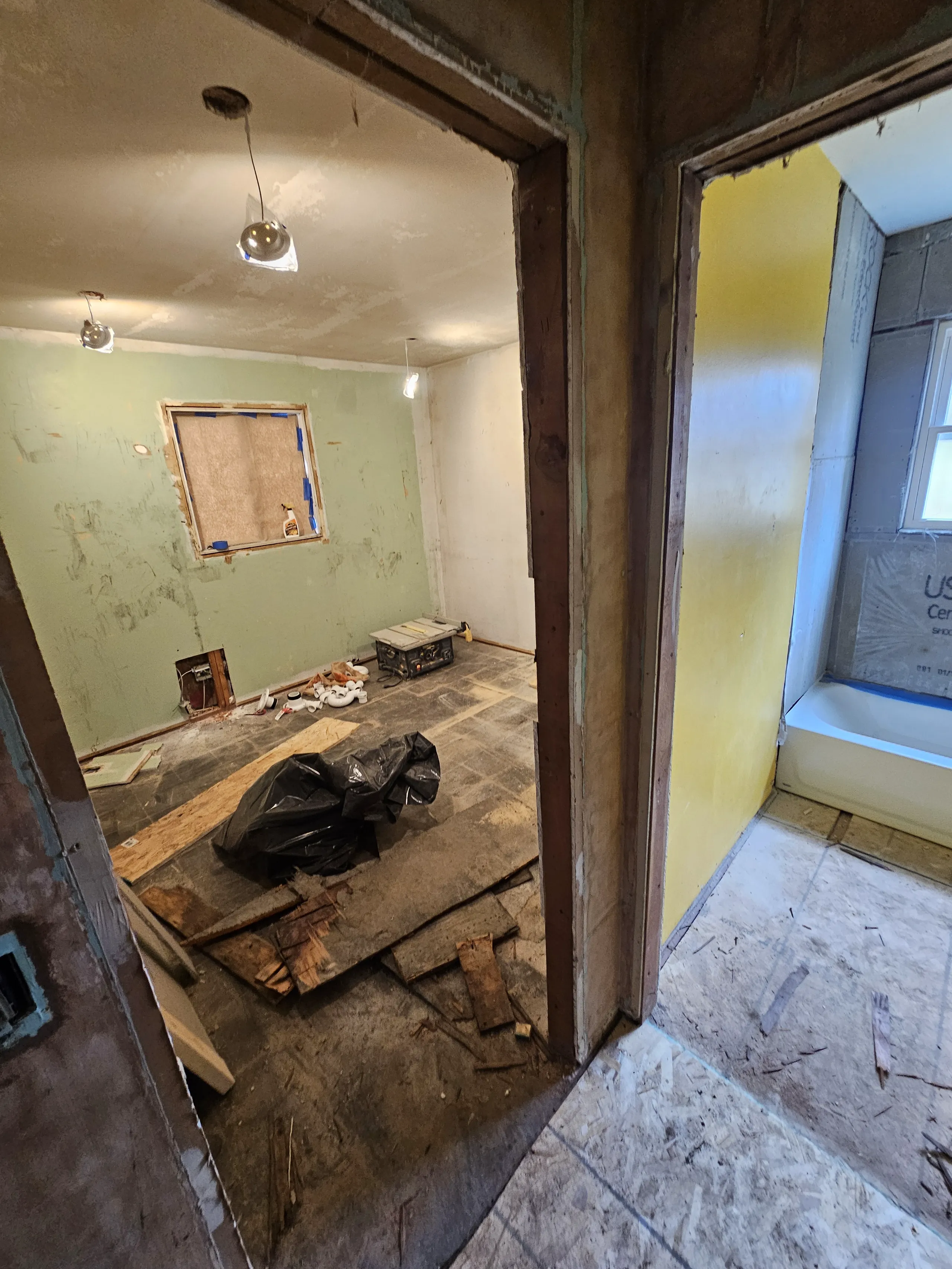 Interior view of an unfinished room, showcasing ongoing renovation work with exposed walls and debris