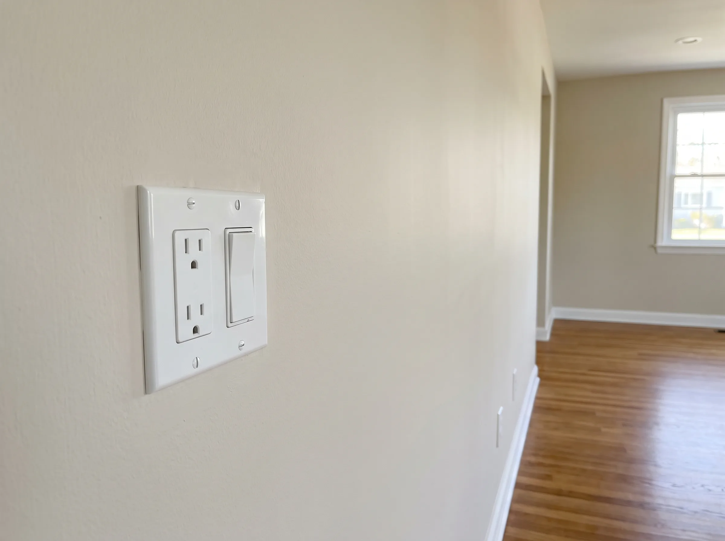 Close-up of an electrical outlet and switch on a newly painted wall in a renovated room