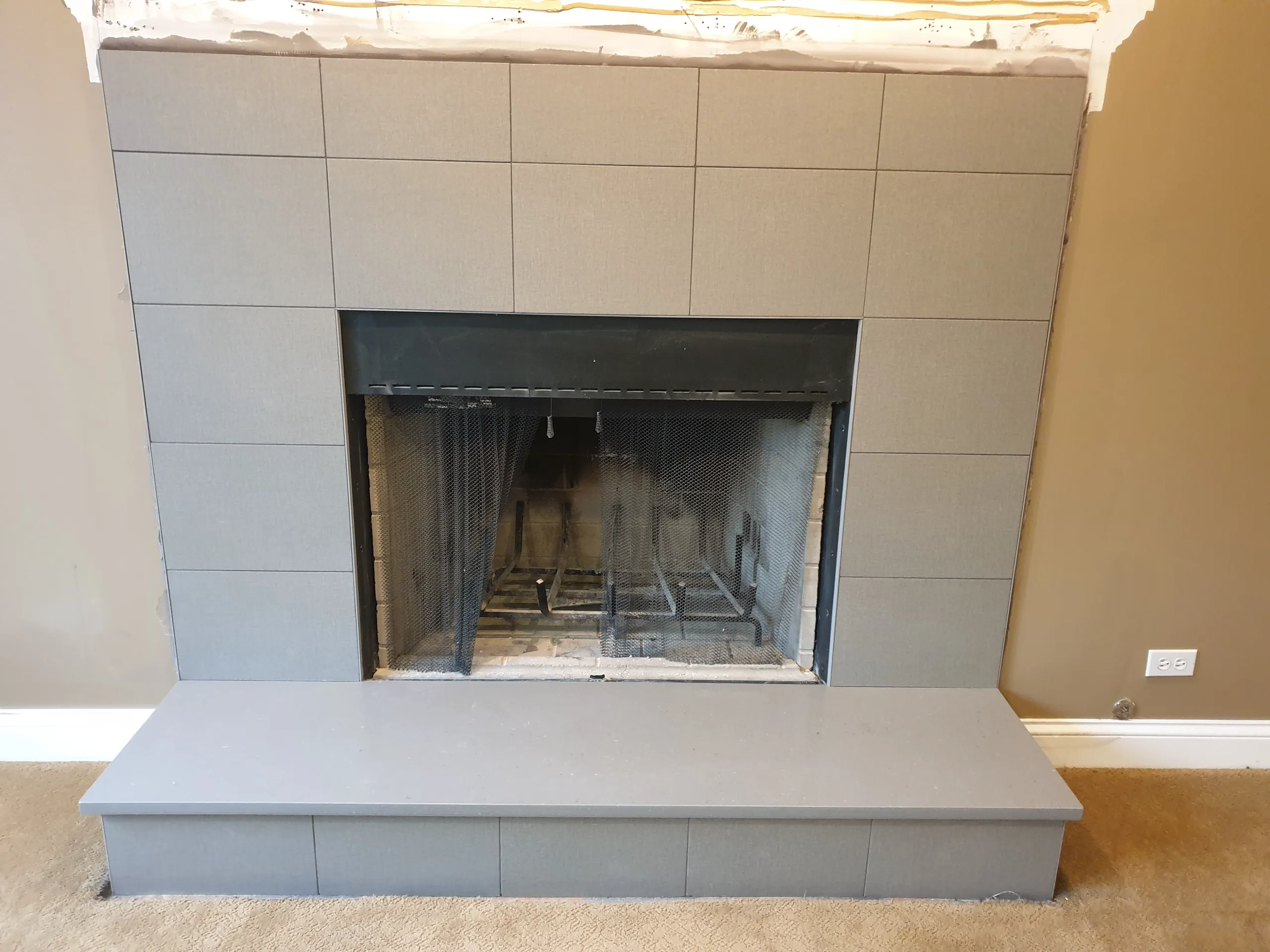 Modern fireplace renovation with gray tile surround and sleek mantel