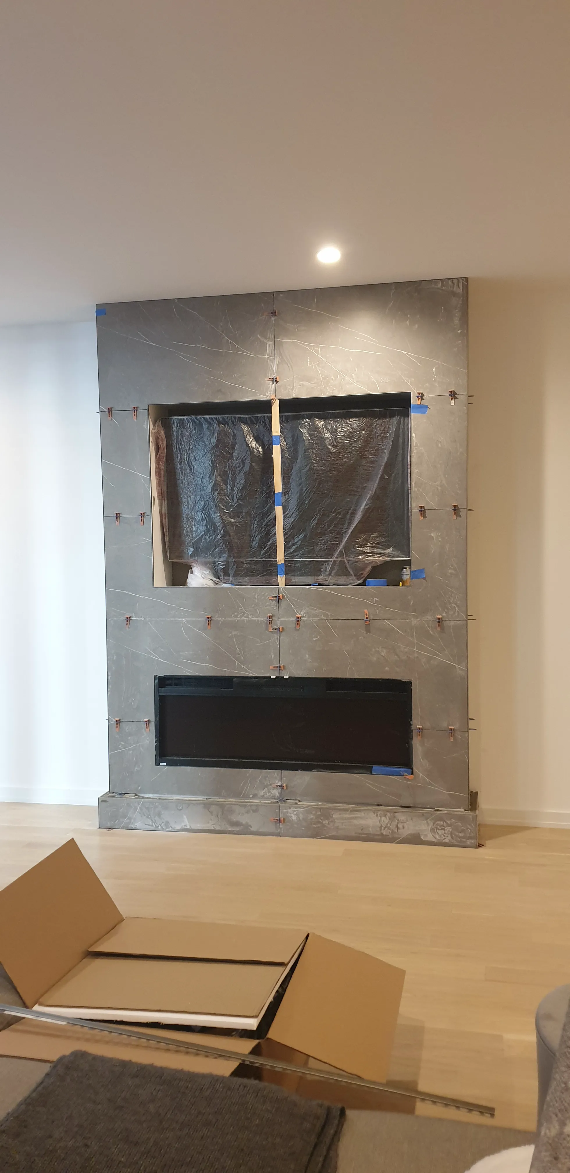 Modern fireplace installation with marble design and plastic covering on wall