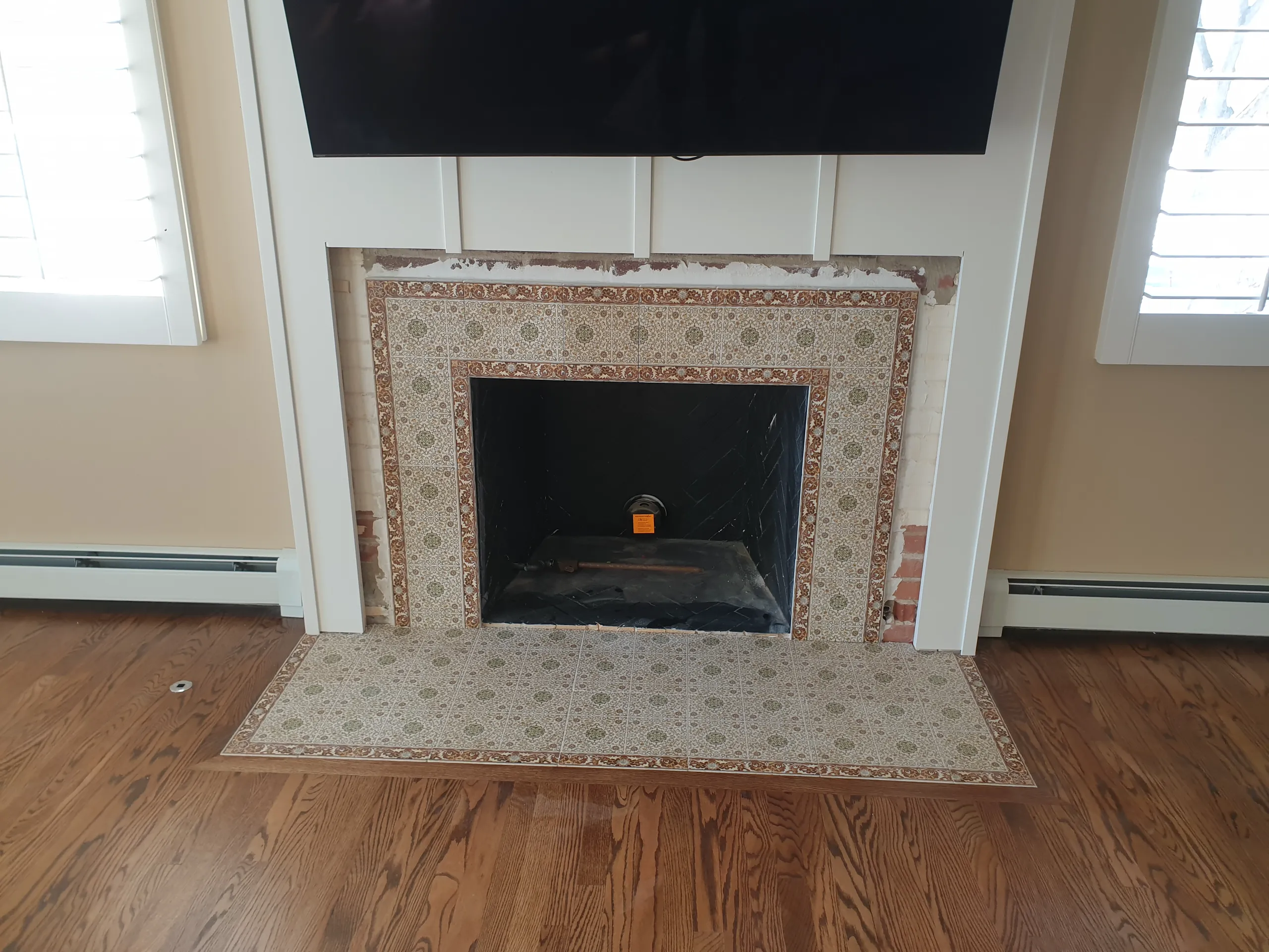 Fireplace installation with decorative tile surround and wooden flooring in a cozy living room setting