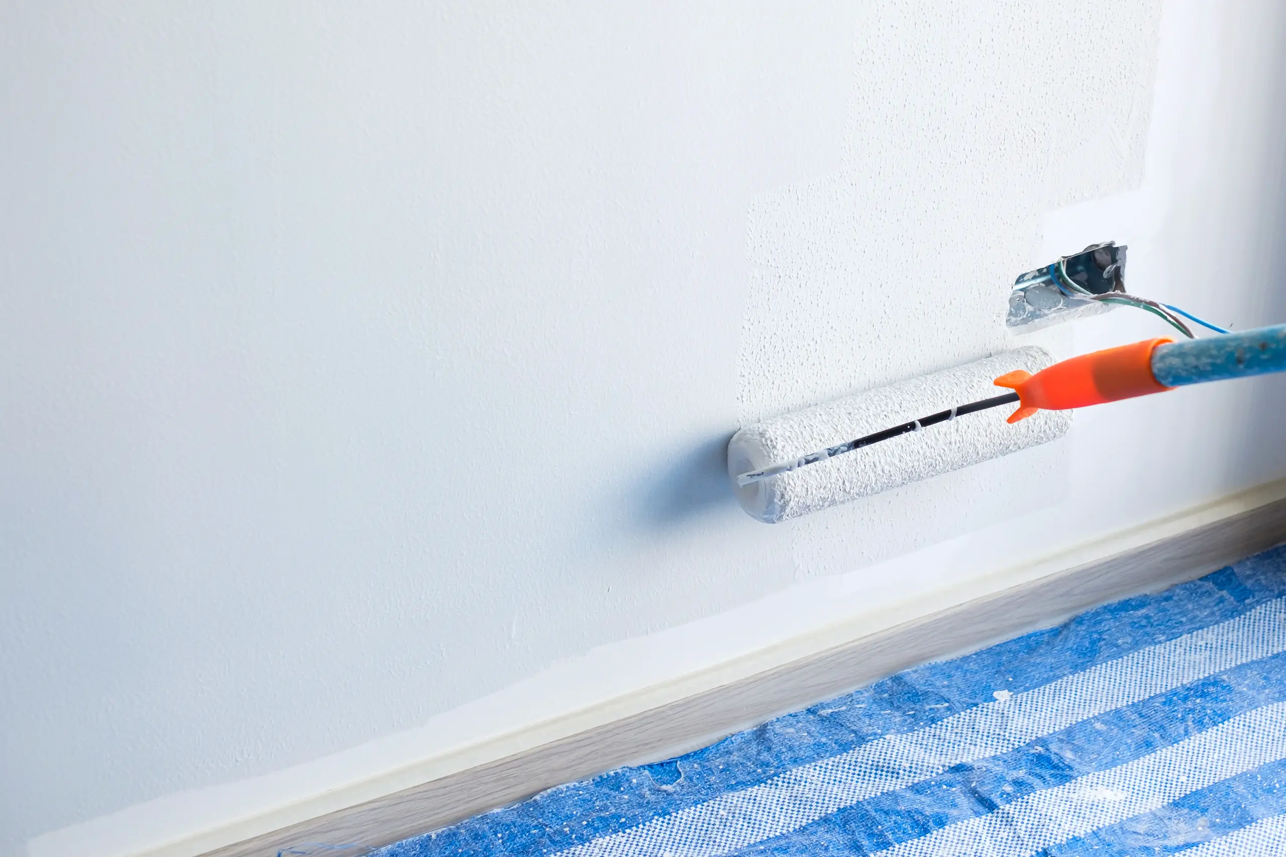 Painting a wall with a roller, showcasing interior painting services