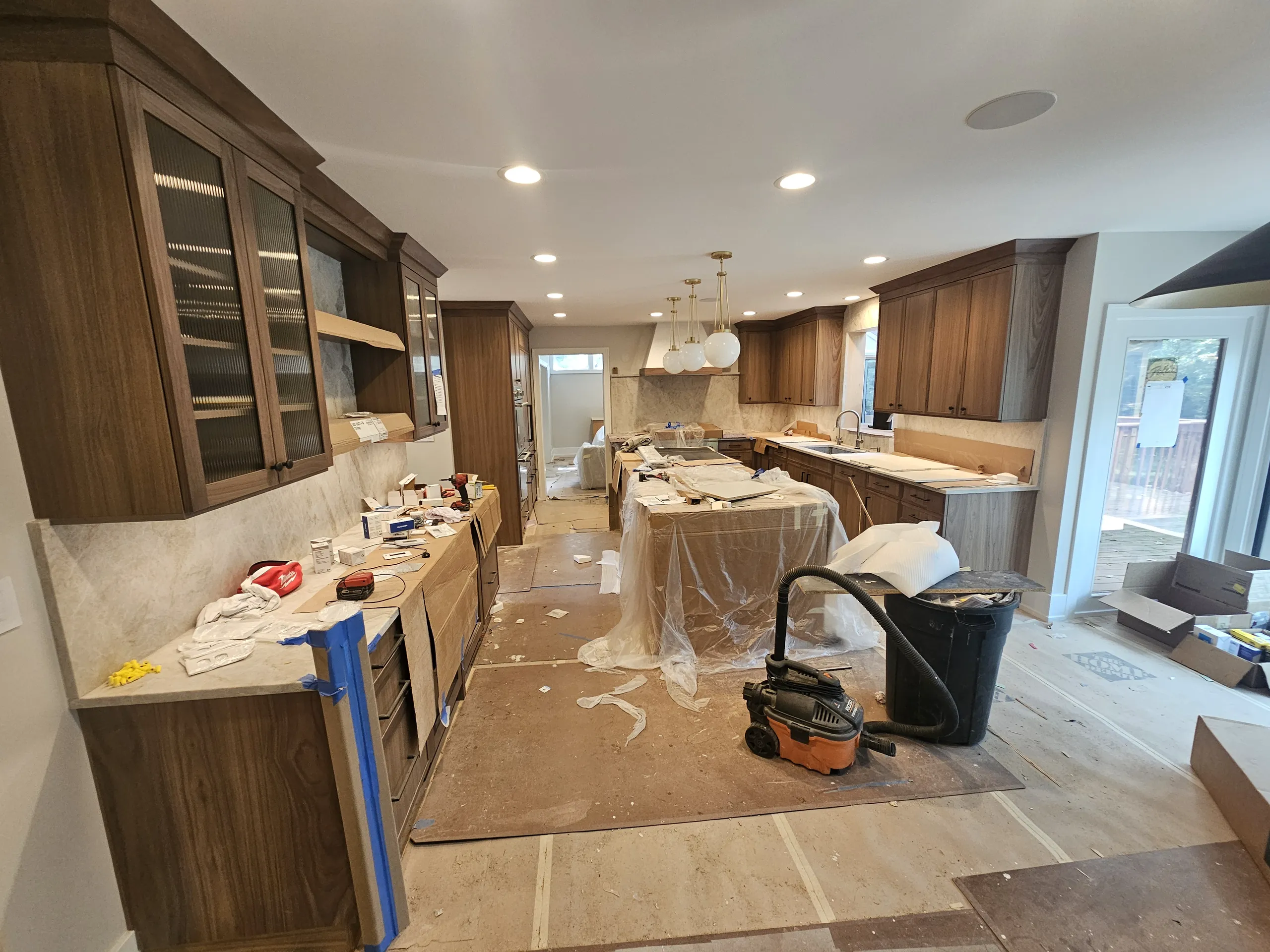 A partially renovated kitchen showing cabinets and countertops with construction materials scattered on the floor