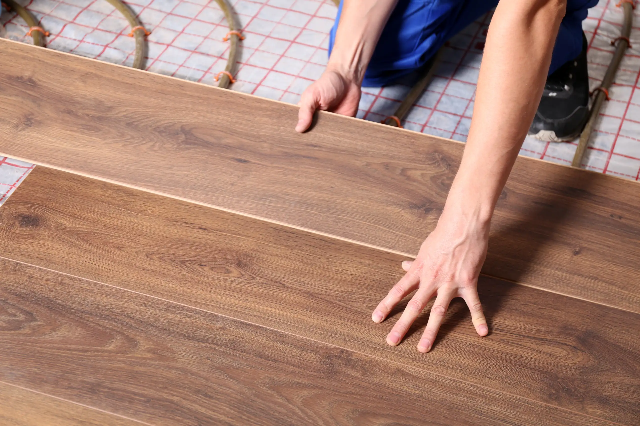 Installation of laminate flooring with hands placing planks carefully on the surface