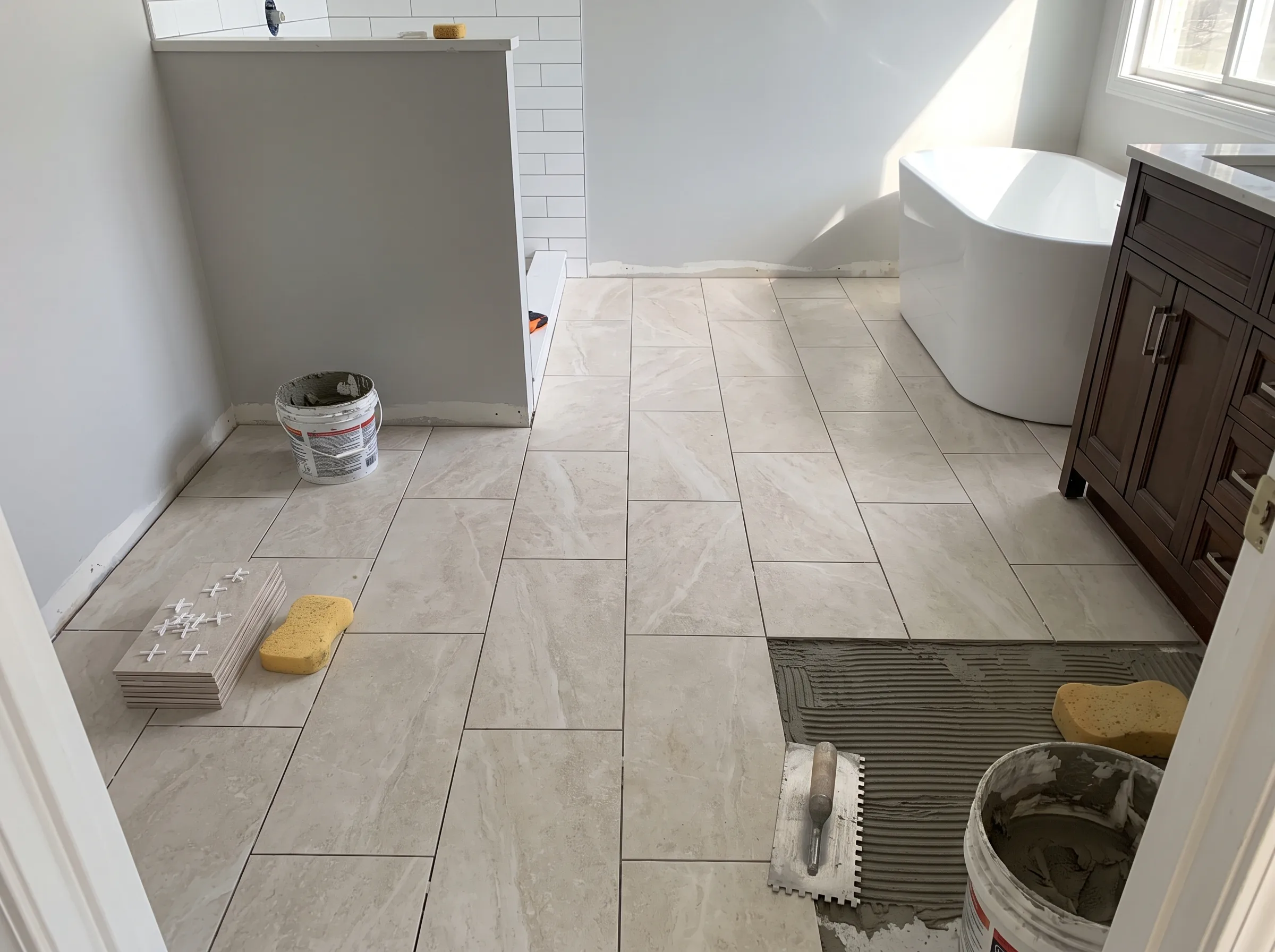 Newly installed floor tiles in a bathroom renovation with a bathtub and vanity