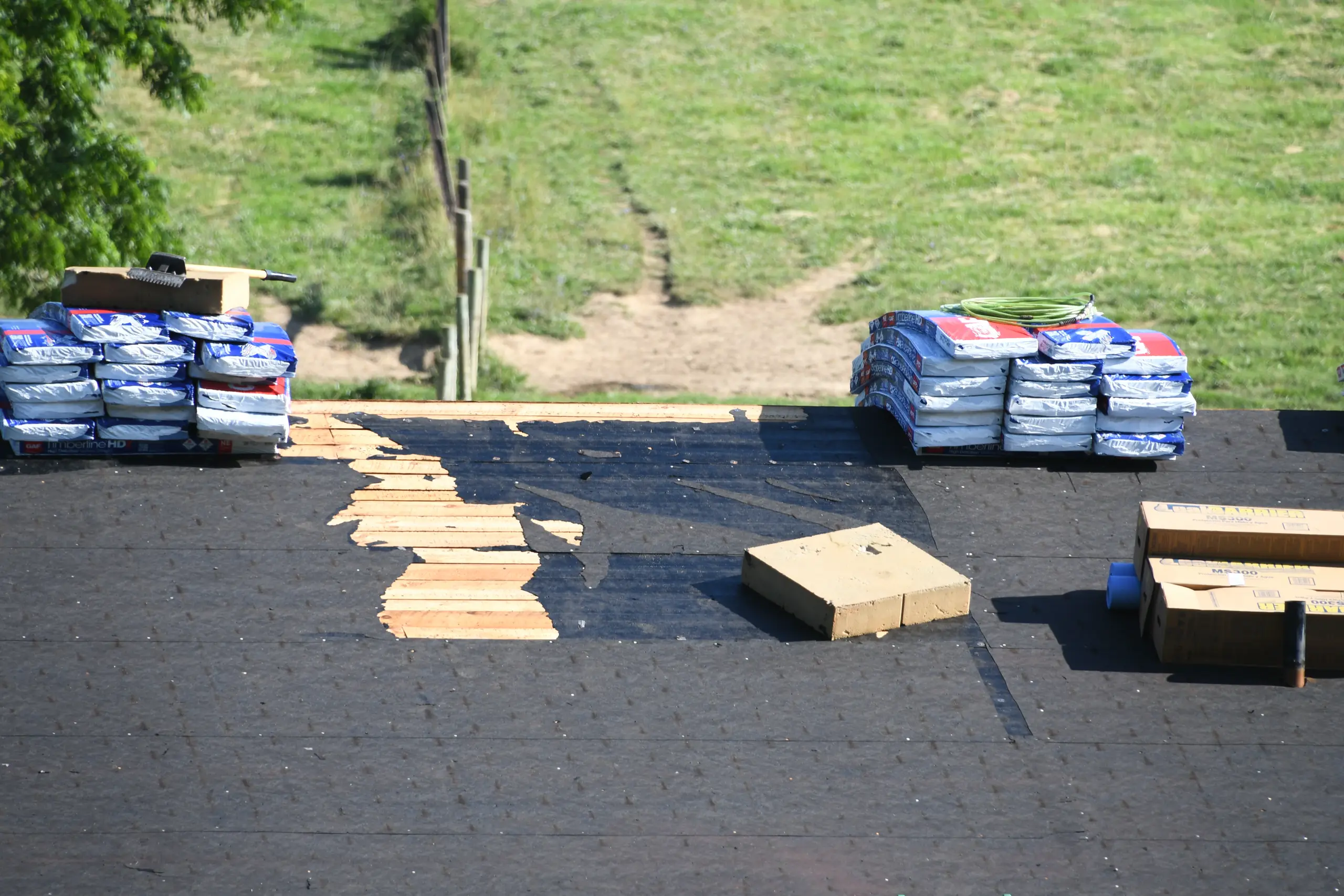 Roof installation in progress with materials like shingles and wooden planks visible