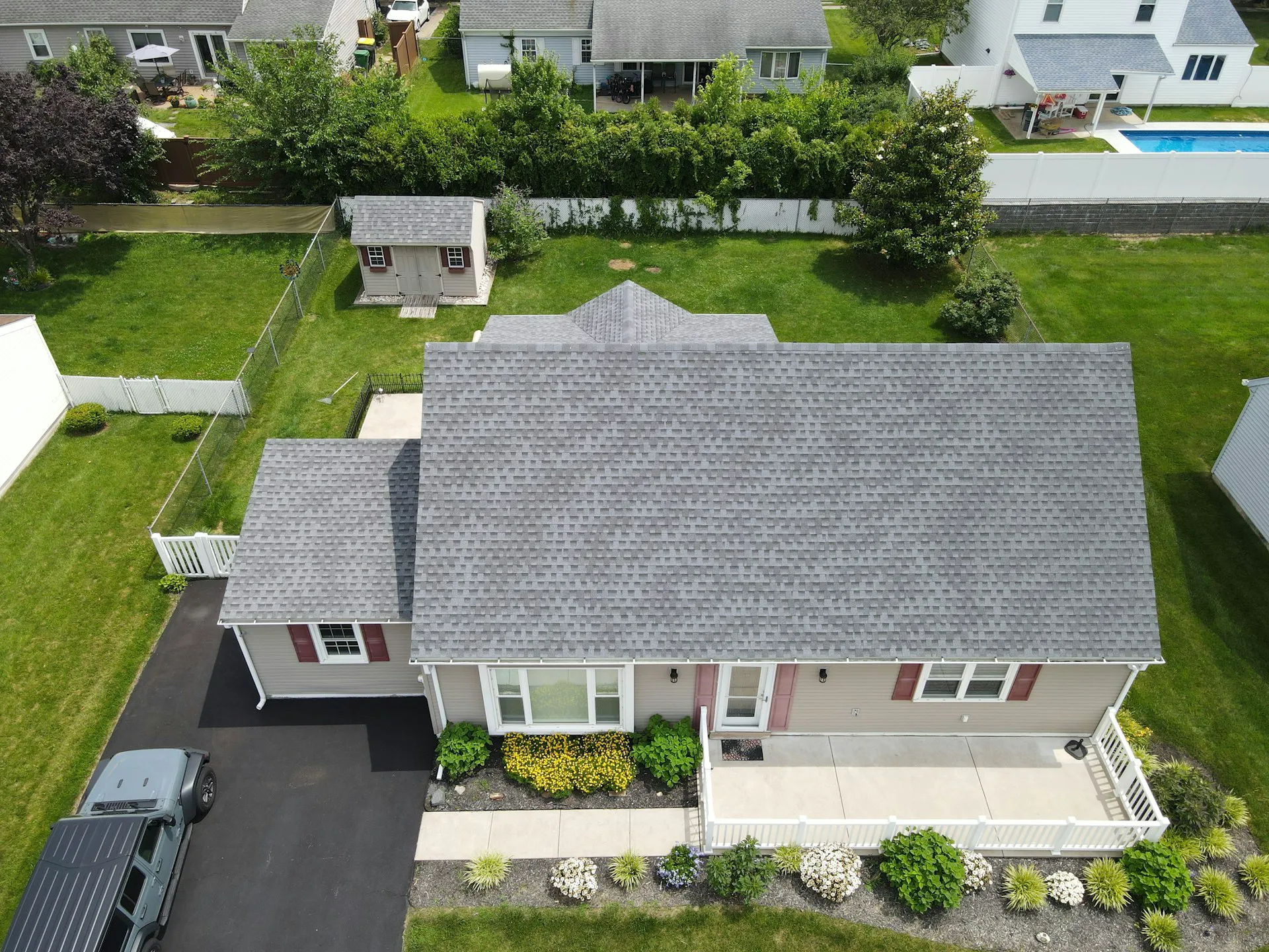 Aerial view of a home showcasing recently installed shingle roofing and landscaped yard