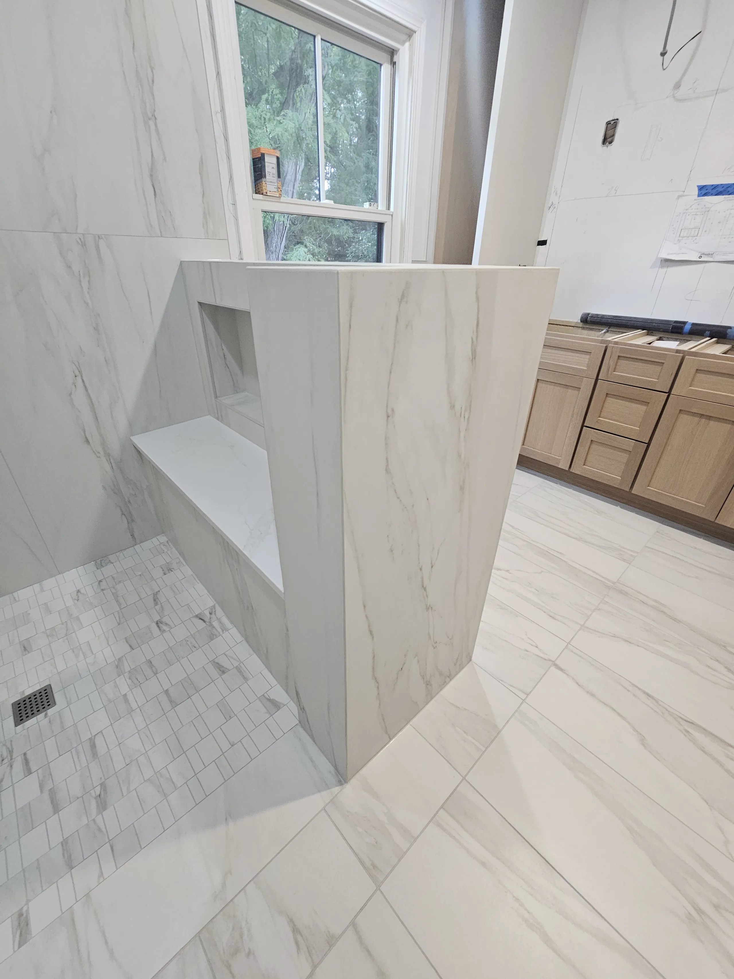 Modern shower remodel featuring elegant marble tiles and a sleek bench