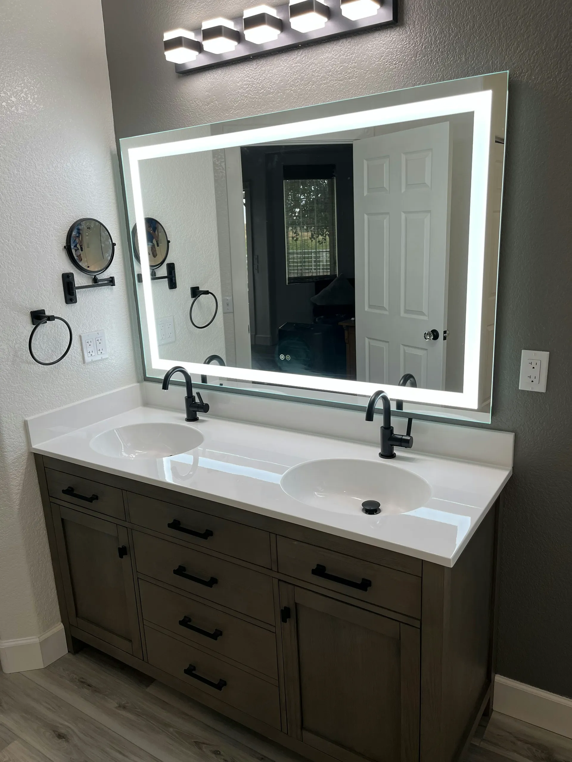 Modern vanity installation with dual sinks and backlit mirror in a bright bathroom