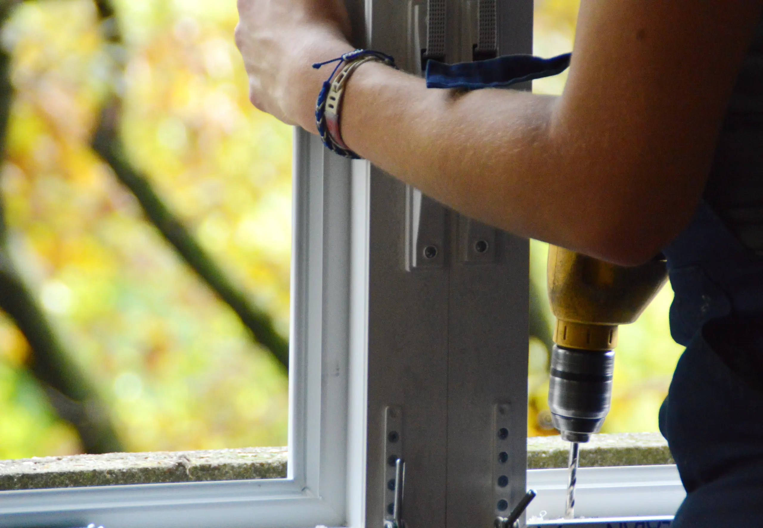 A person installing a window with a drill in a bright environment